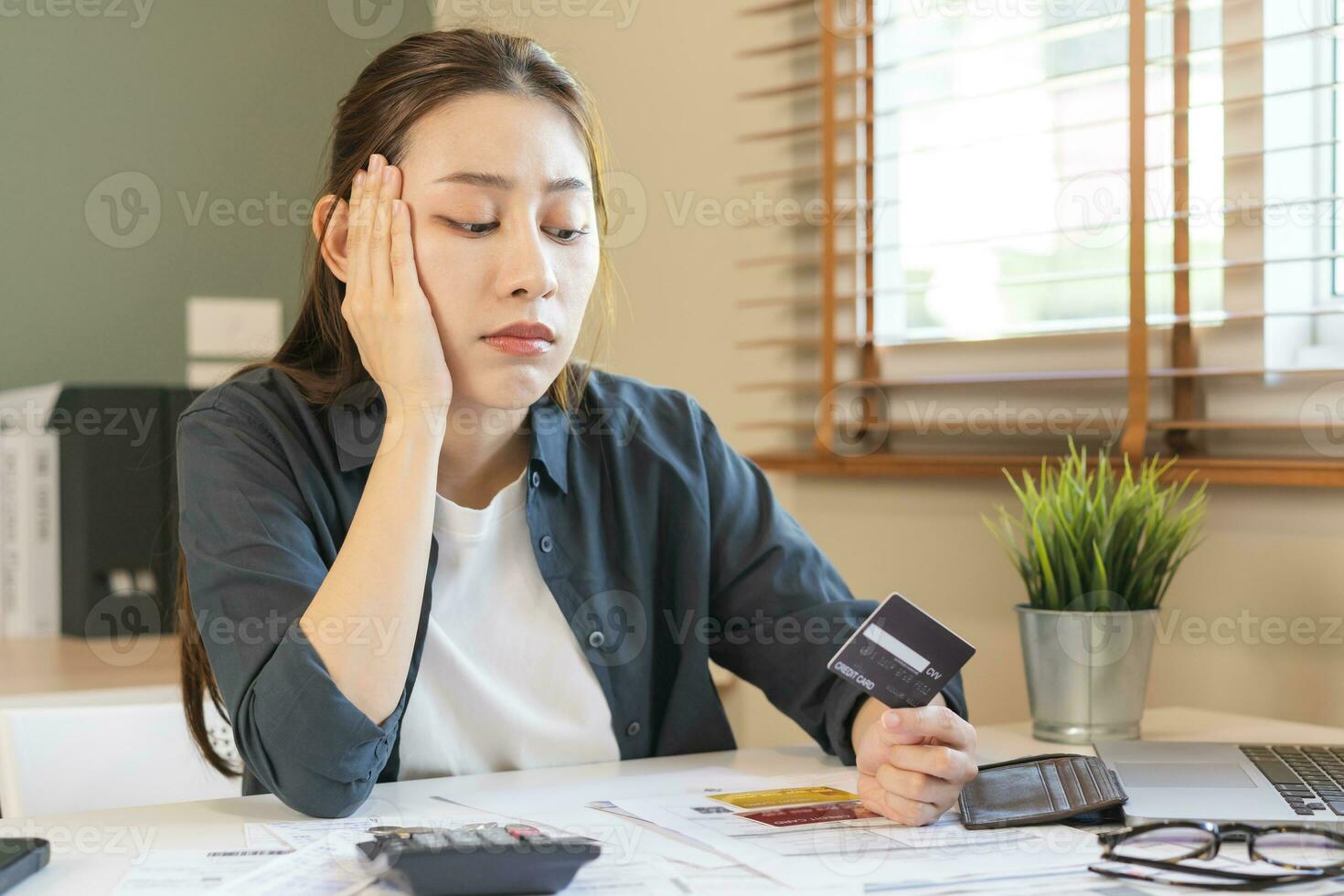 Financial owe, hand of asian woman sitting, holding many credit card, stressed  by calculate expense from invoice or bill, no money to pay, mortgage or loan. Debt, bankruptcy or bankrupt photo