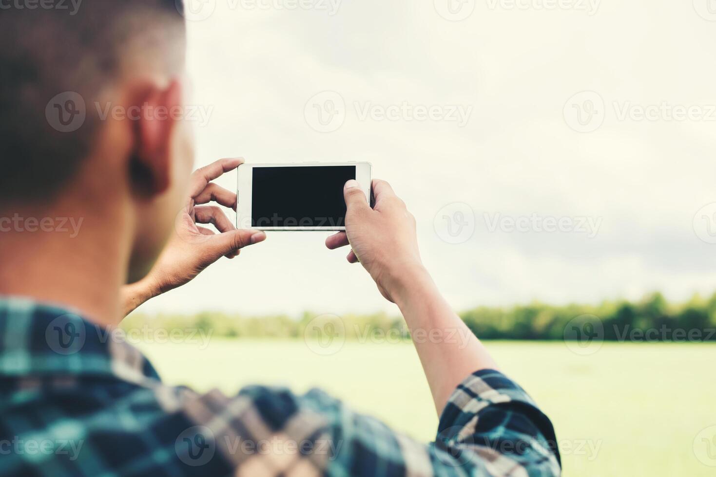 Young hipster man using smartphone taking the landscape photogra photo