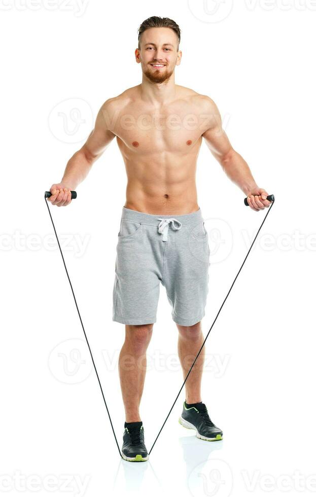 Athletic attractive man jumping on a rope on the white photo