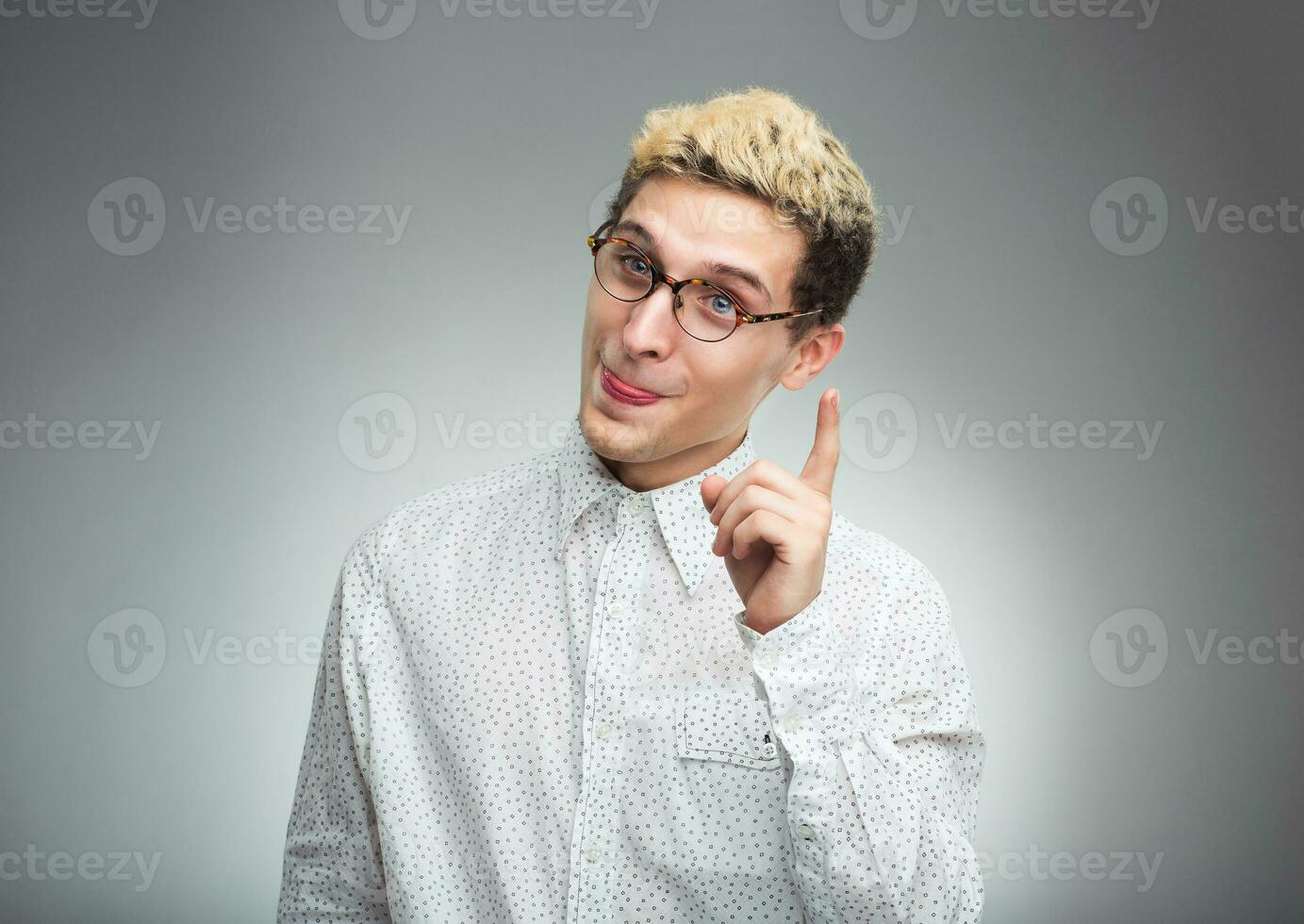 Young man in glasses with a funny expression on his face and thumbs up photo