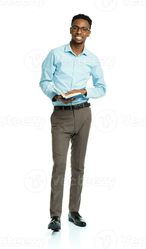 Happy african american college student with books in his hands  standing on white photo