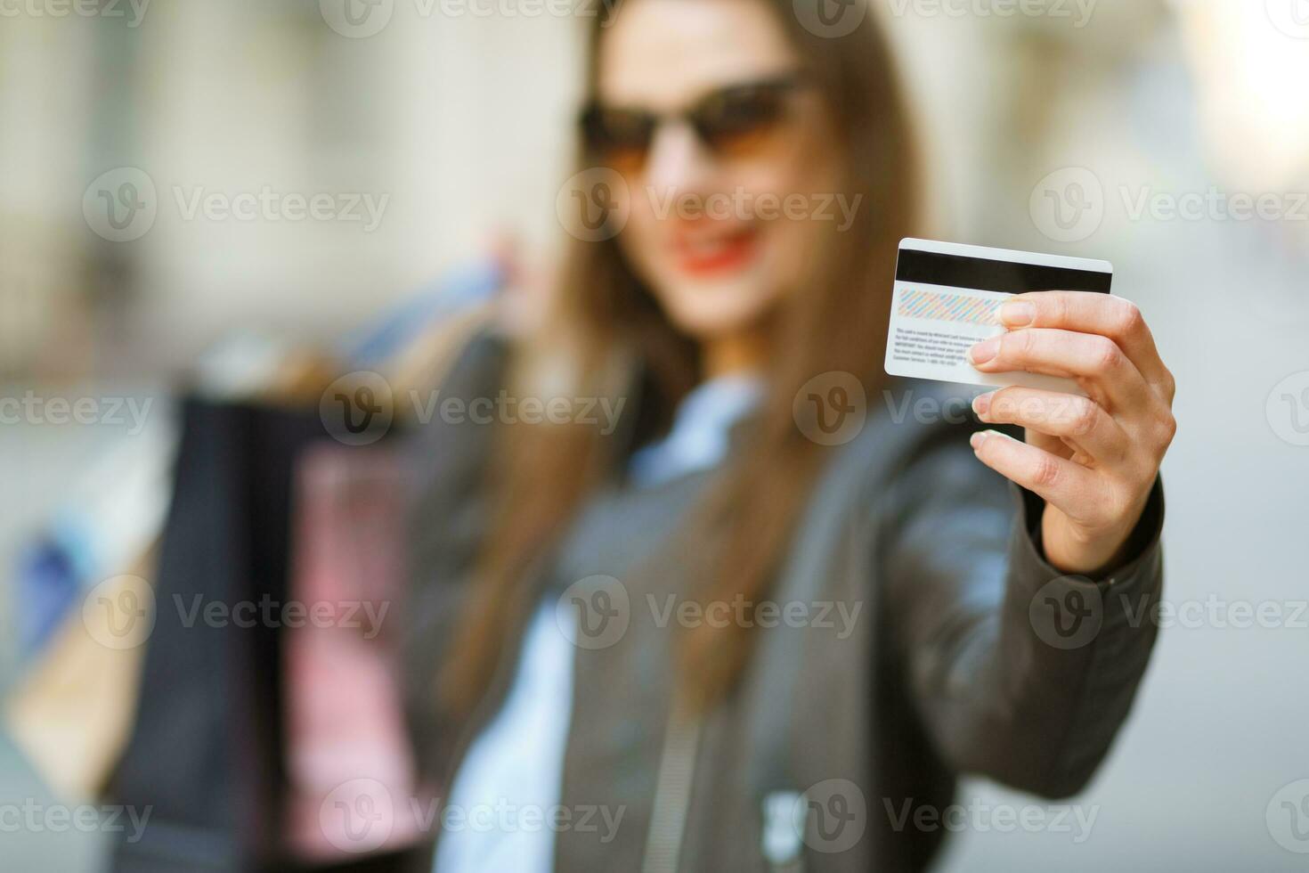 hermosa mujer con compras pantalones y crédito tarjeta en el manos en un calle foto