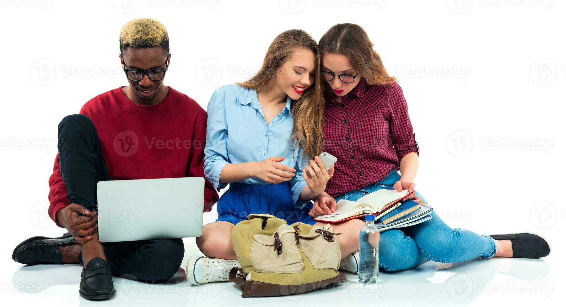 Tres estudiantes sentado con libros, ordenador portátil y pantalones aislado en blanco antecedentes foto