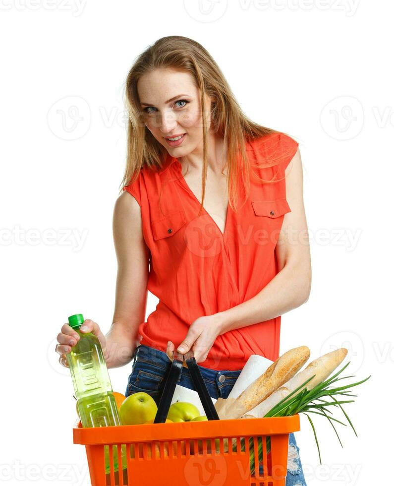 Young caucasian woman with assorted grocery products in shopping basket isolated on white photo