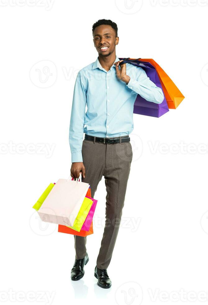 Happy african american man holding shopping bags on white background photo