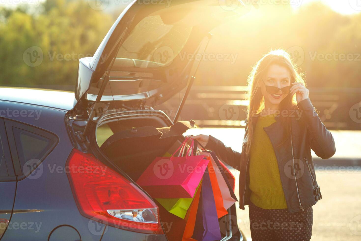 Caucasian woman putting her shopping bags into the car trunk photo