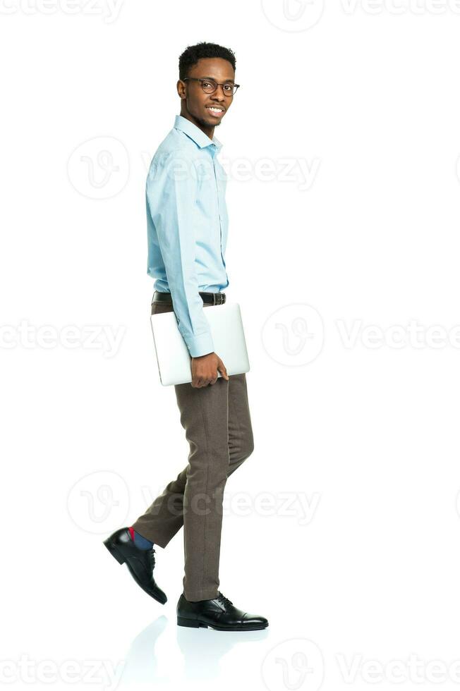 Happy african american college student with laptop standing on white photo