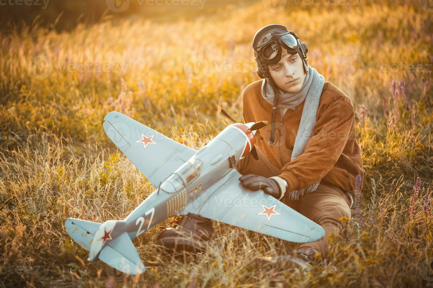 chico en Clásico ropa piloto con un avión modelo al aire libre foto