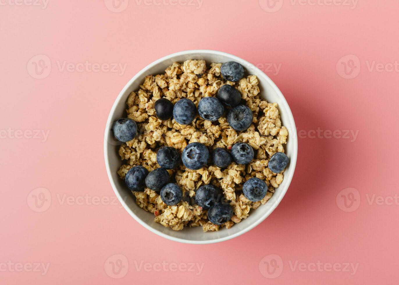 Granola with blueberry in bowl on pink background. photo