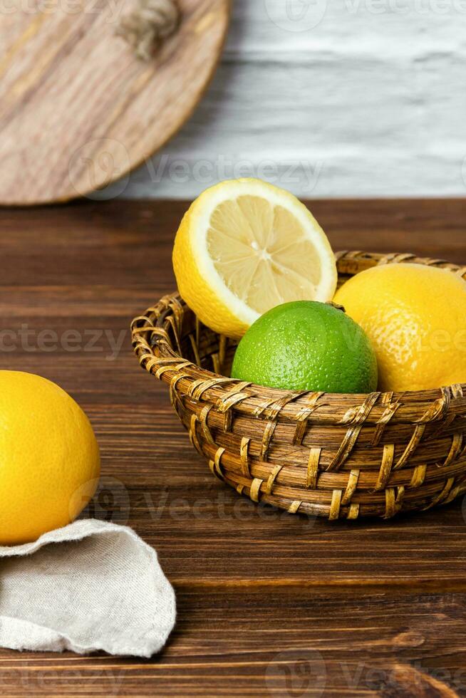 Lemons and limes in basket on wooden table. photo