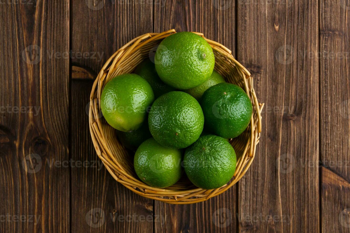 Limes in the basket with copy space on wooden background. photo