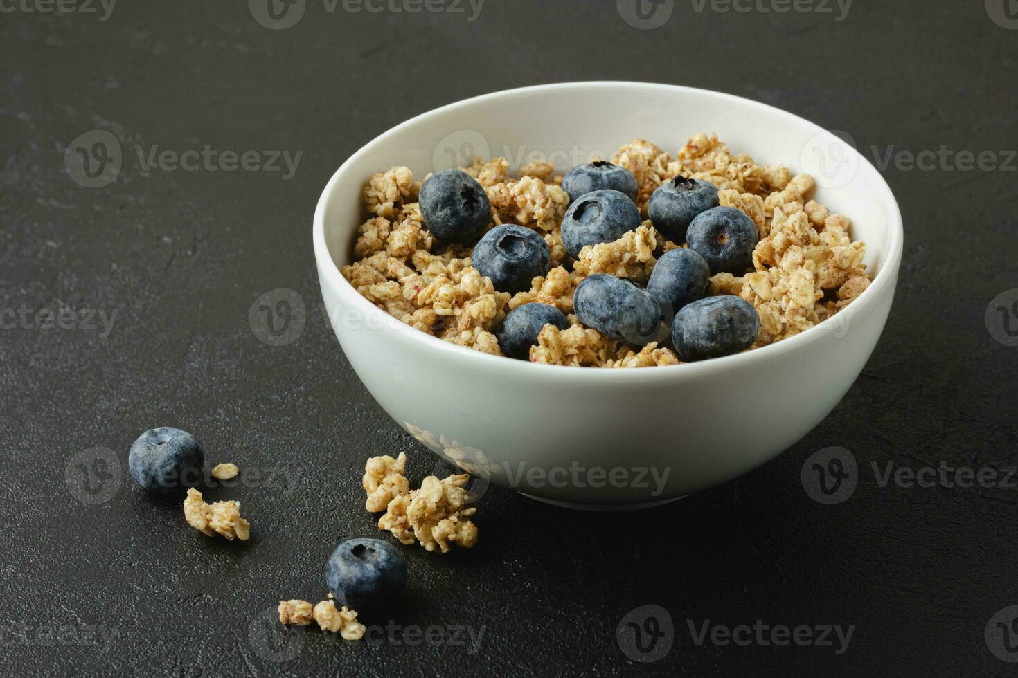 Granola with blueberry in white bowl. photo