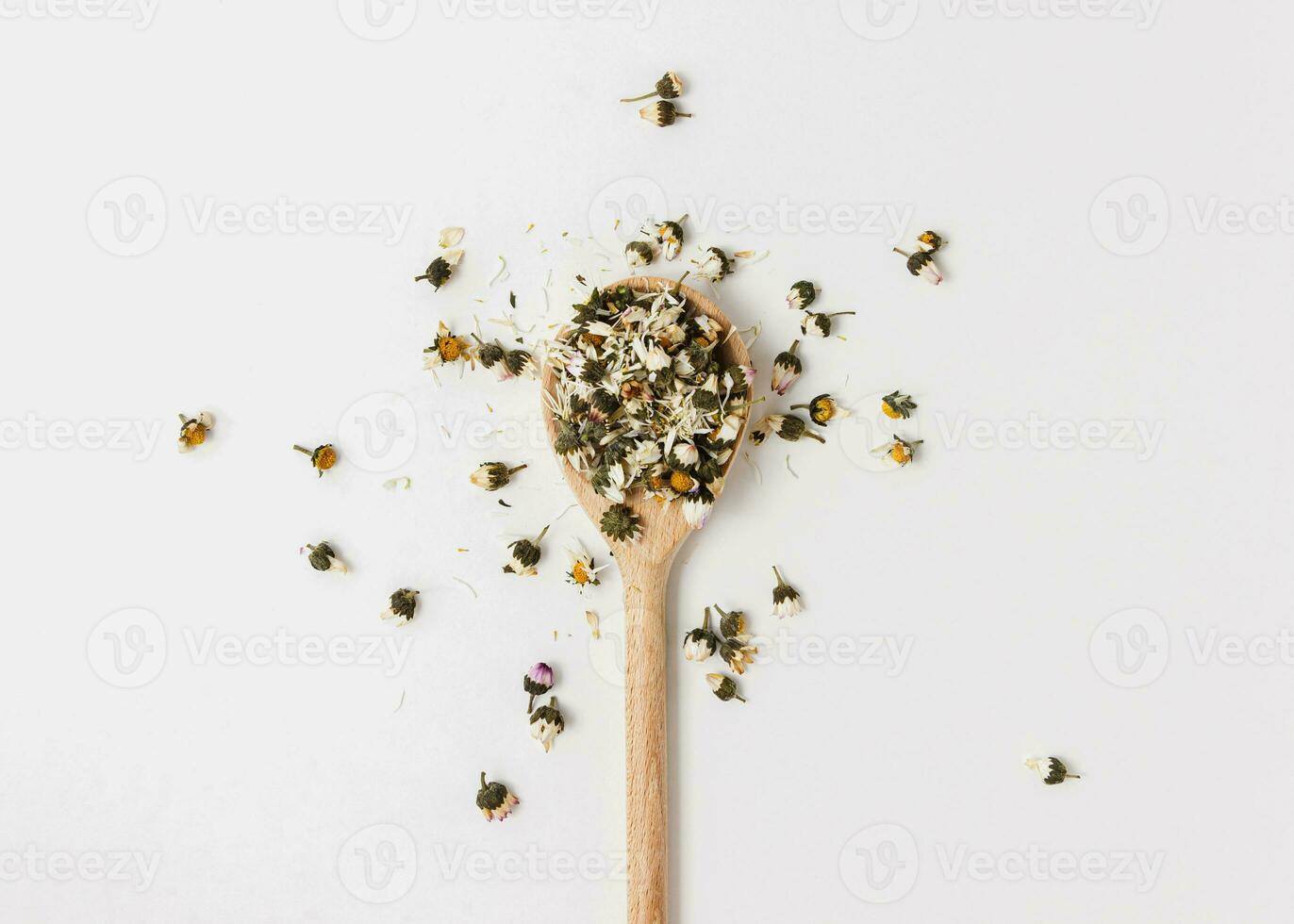 Dry chamomile tea on wooden spoon on white background. photo