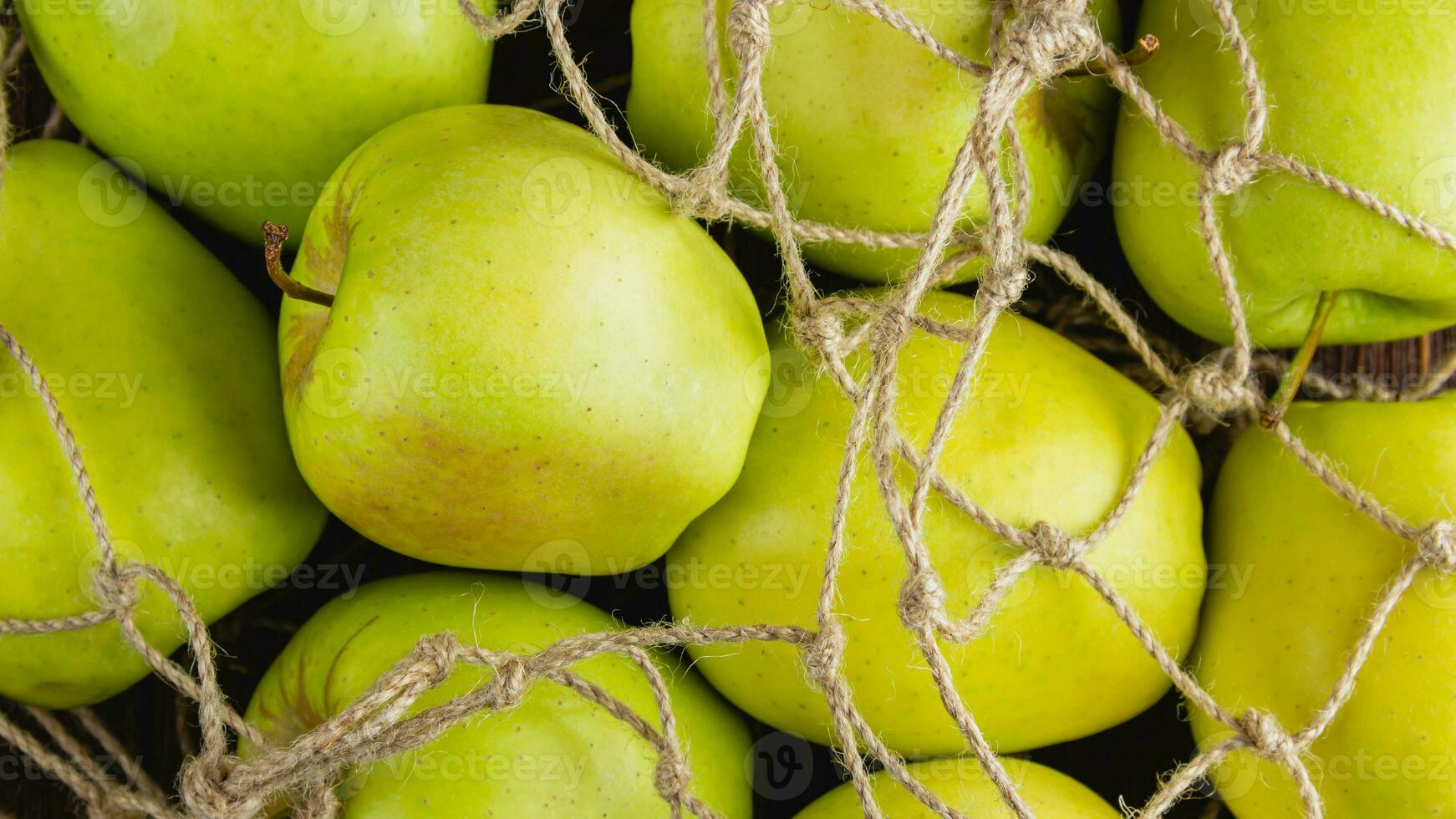 Yellow apples in a grid bag on a wooden background photo