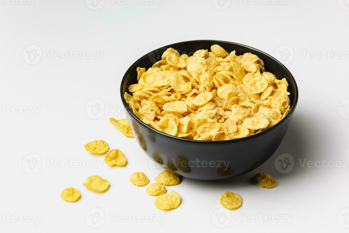 Corn flakes in dark bowl on white background. photo