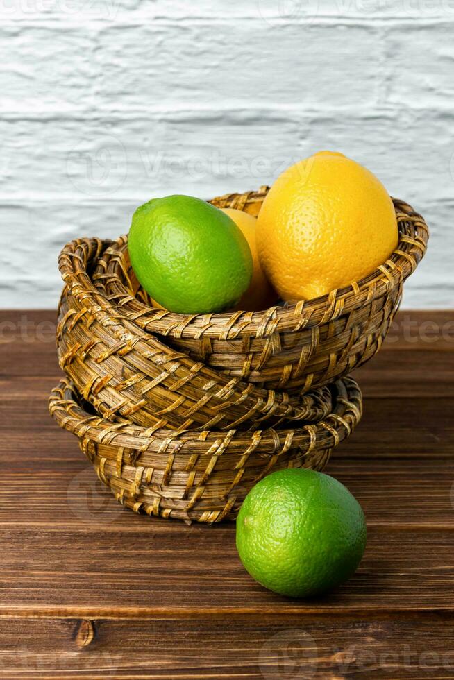 Lemons and limes in baskets on wooden table. photo