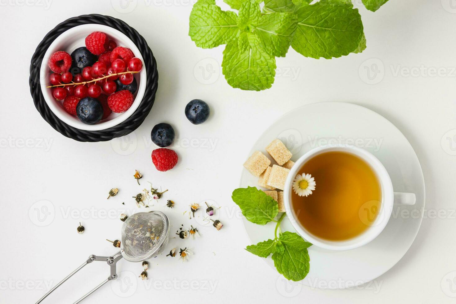 Chamomile tea with mint and berries in black basket on white background. photo