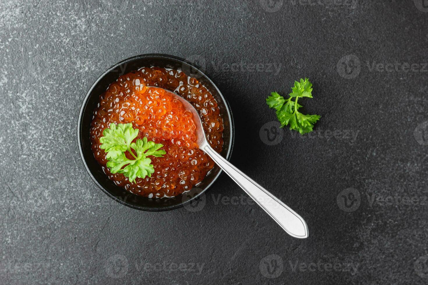 caviar de salmón rojo con perejil en un bol foto