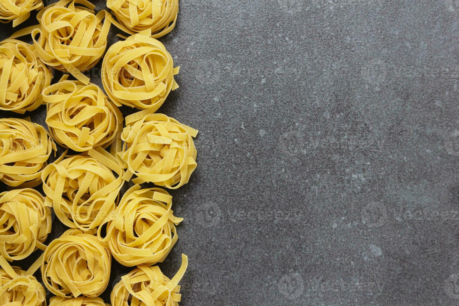 Raw pasta tagliatelle with copy space on concrete background. photo