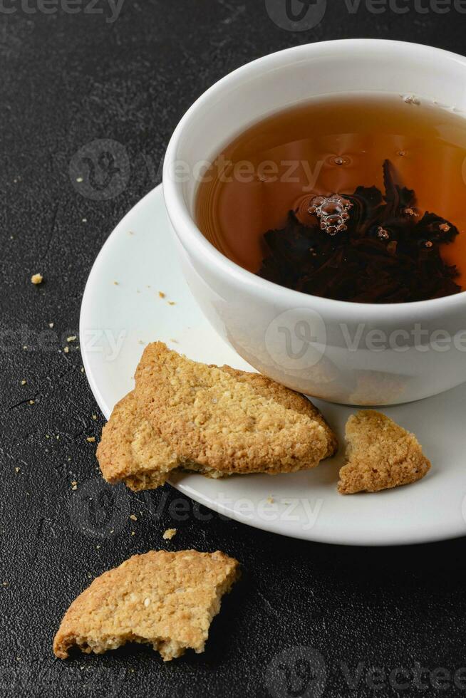 taza de negro té con avena galletas en oscuro antecedentes. foto