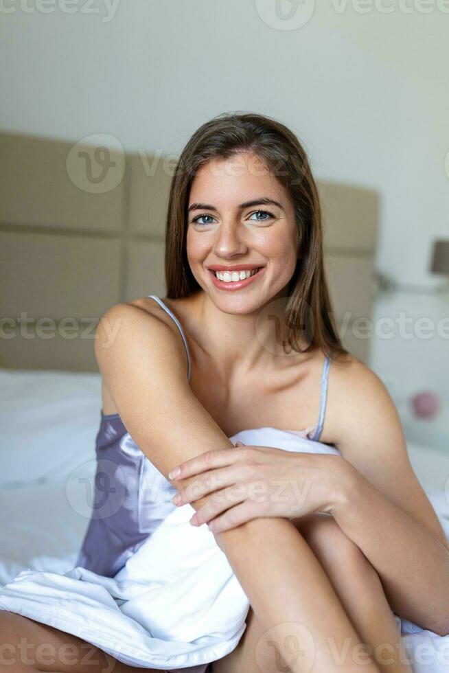 Portrait pretty young woman on bed in modern apartment in the morning. Lovely woman posing in a bedroom and looks satisfied. photo