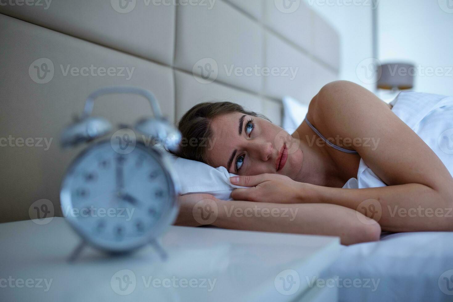 mujer con insomnio acostada en la cama con los ojos abiertos. chica en la cama que sufre insomnio y trastorno del sueño pensando en su problema por la noche foto