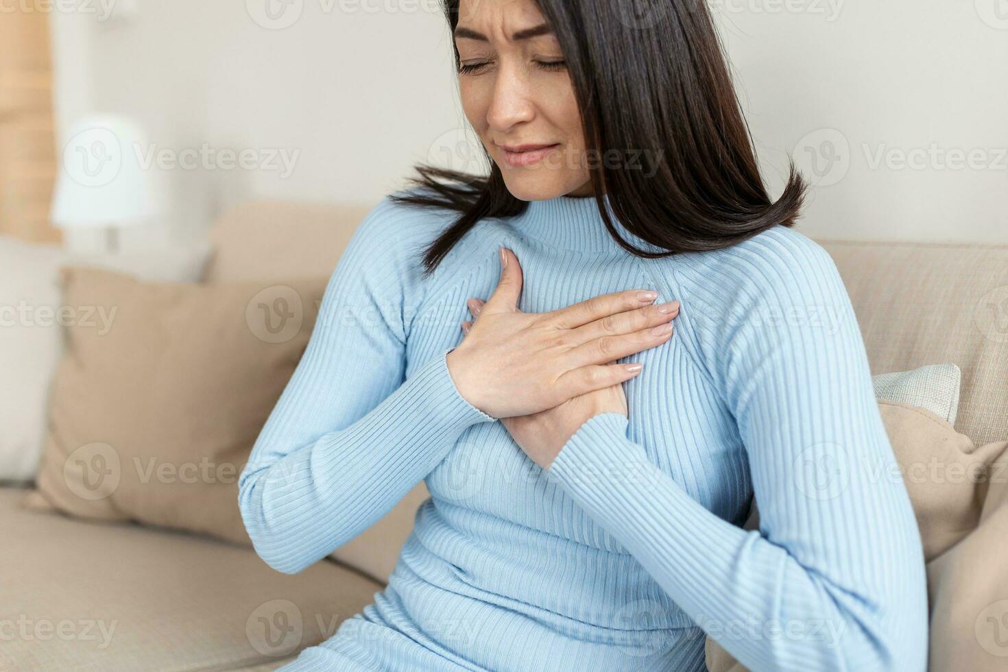Asian beautiful woman sick with feeling pain in the chest. Hand holding chest after taking a medication.Concept of hard work without maintaining health. photo