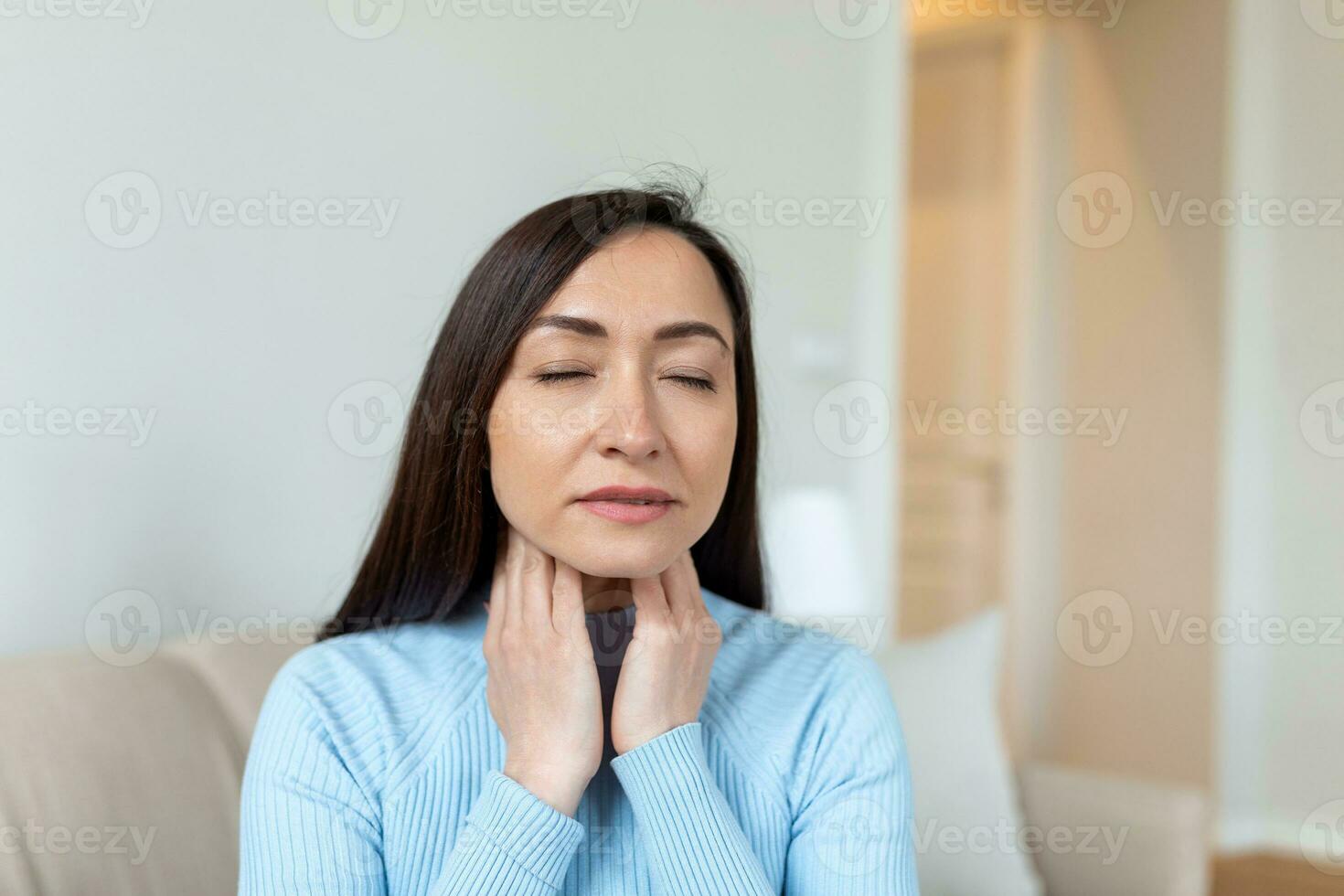 Close up of Asian woman rubbing her inflamed tonsils, tonsilitis problem, cropped. Woman with thyroid gland problem, touching her neck, woman has a sore throat photo