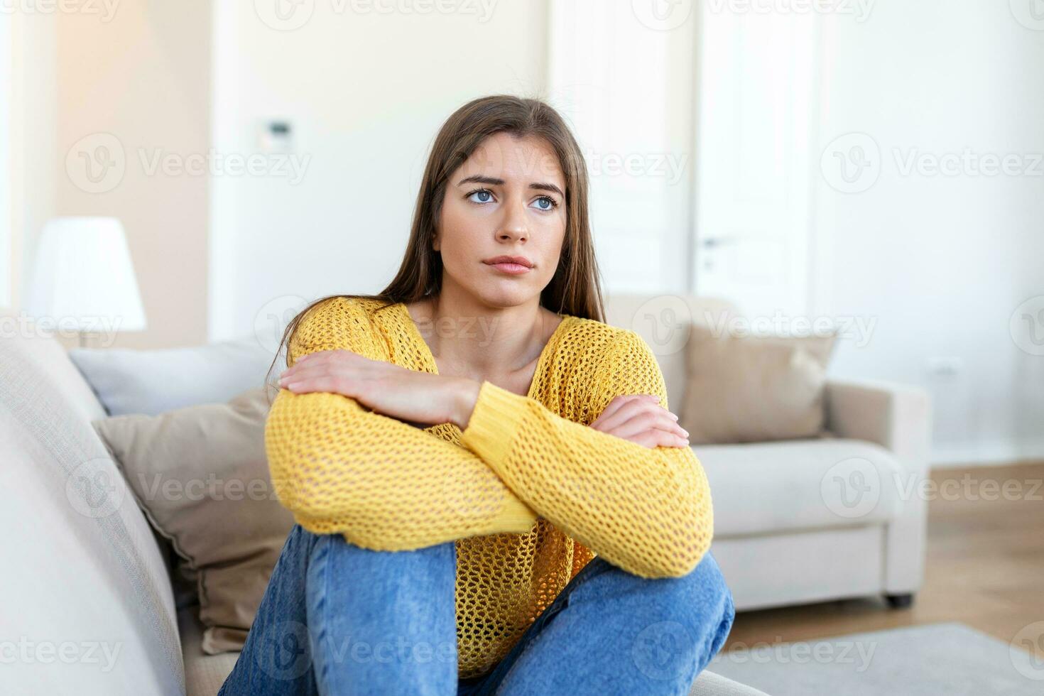anxious worried woman sitting on couch at home. Frustrated confused female feels unhappy, problems in personal life, quarrel break up with boyfriend and unexpected pregnancy concept photo