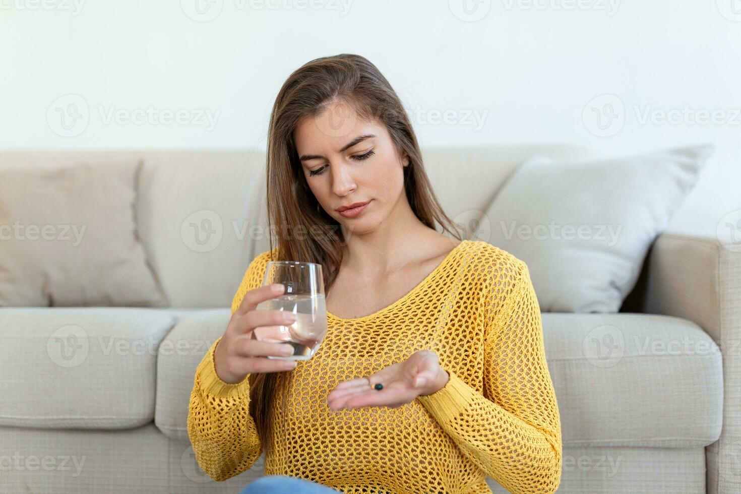 Head shot smiling young woman holding pill and glass of fresh pure water. Healthy millennial lady taking antioxidant medicine vitamins, beauty supplements for hair skin nails, healthcare concept. photo