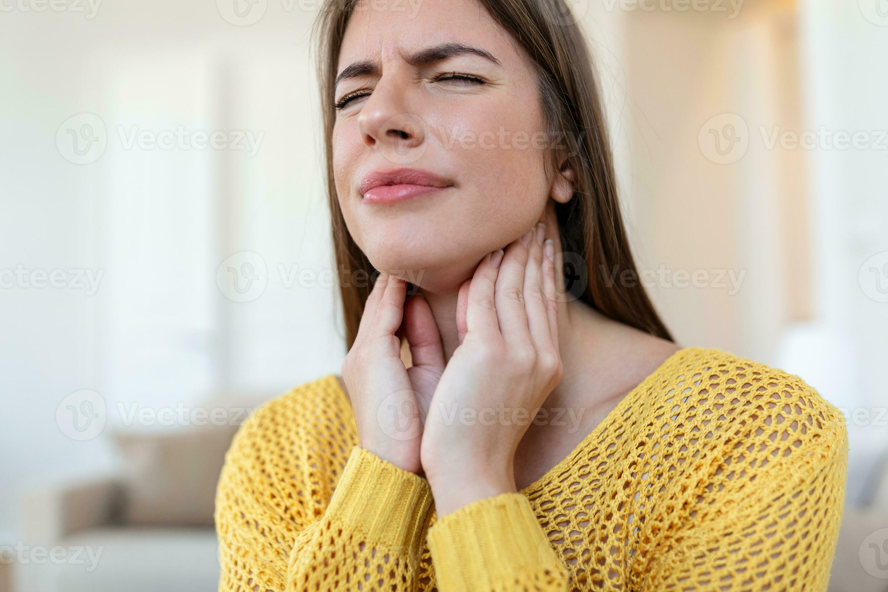 Close up of young woman rubbing her inflamed tonsils, tonsilitis
