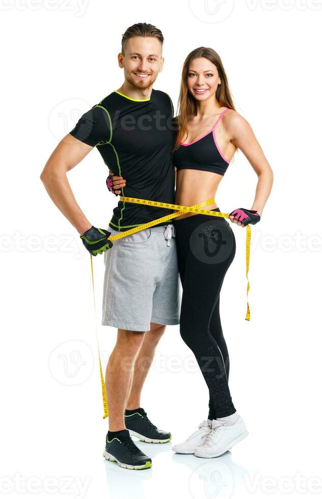 Happy athletic couple - man and woman with measuring tape on the white photo
