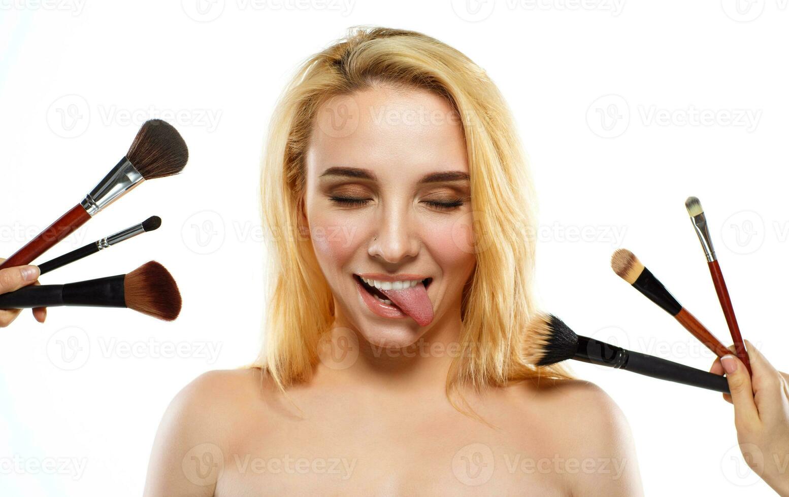 gracioso joven mujer con maquillaje cepillos cerca su cara foto