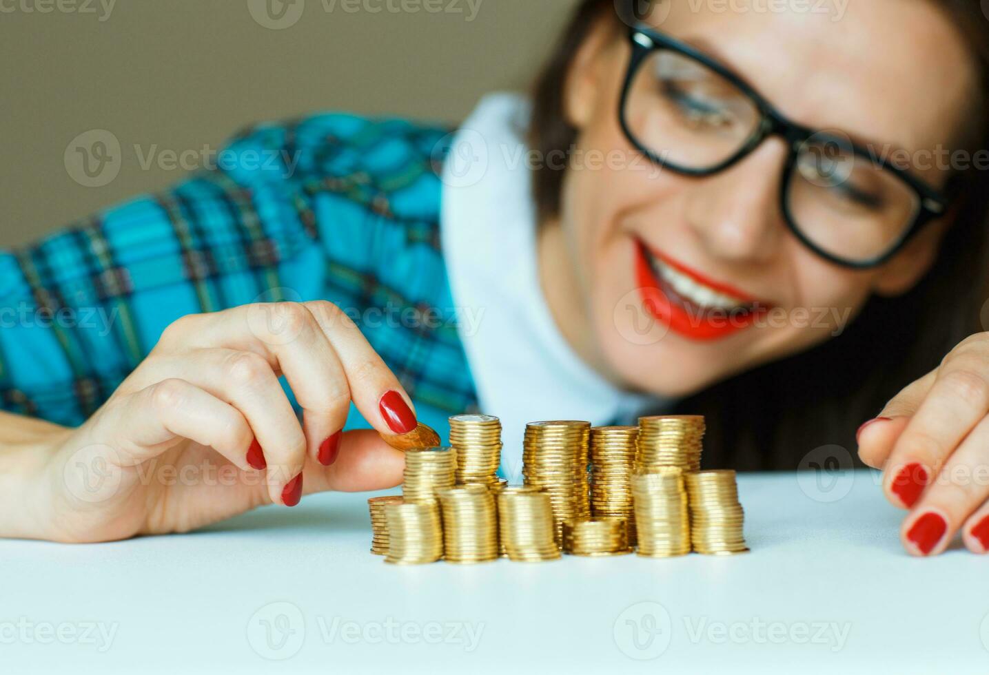 Smiling woman stacking gold coins into columns photo