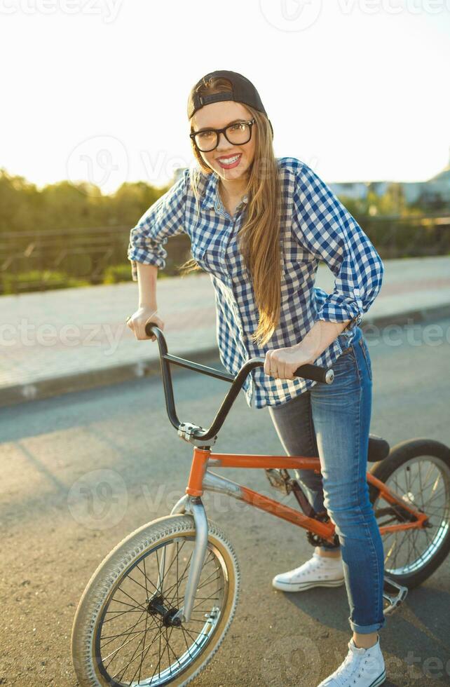 Lovely young woman in a hat riding a bicycle on city background in the sunlight outdoor photo