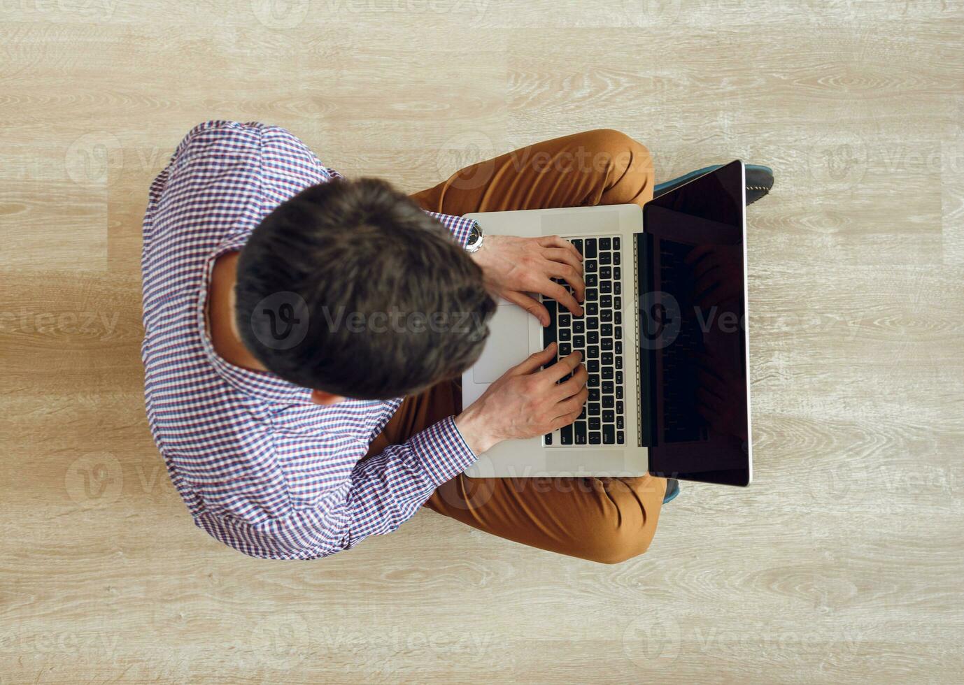 Top view of man sitting on the floor and working with a laptop photo