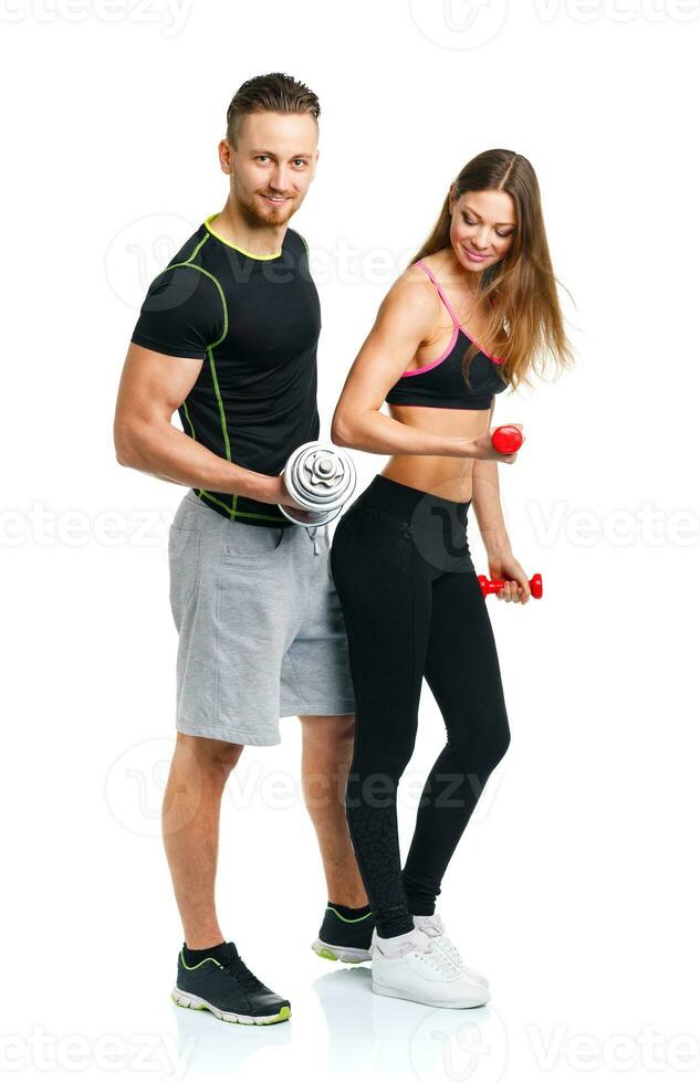 Athletic couple - man and woman with dumbbells on the white photo