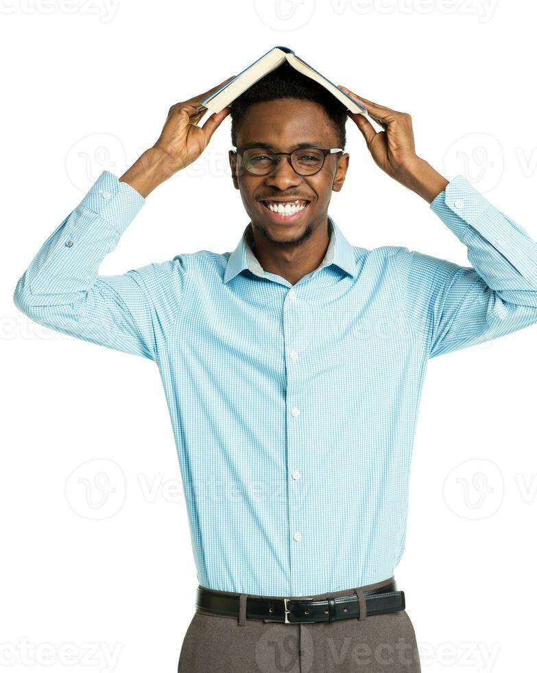 Happy african american college student with book on his head standing on white photo
