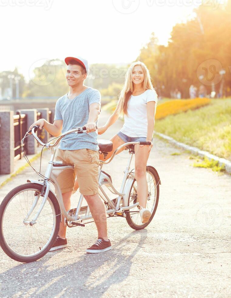 contento Pareja montando un bicicleta en el parque al aire libre foto