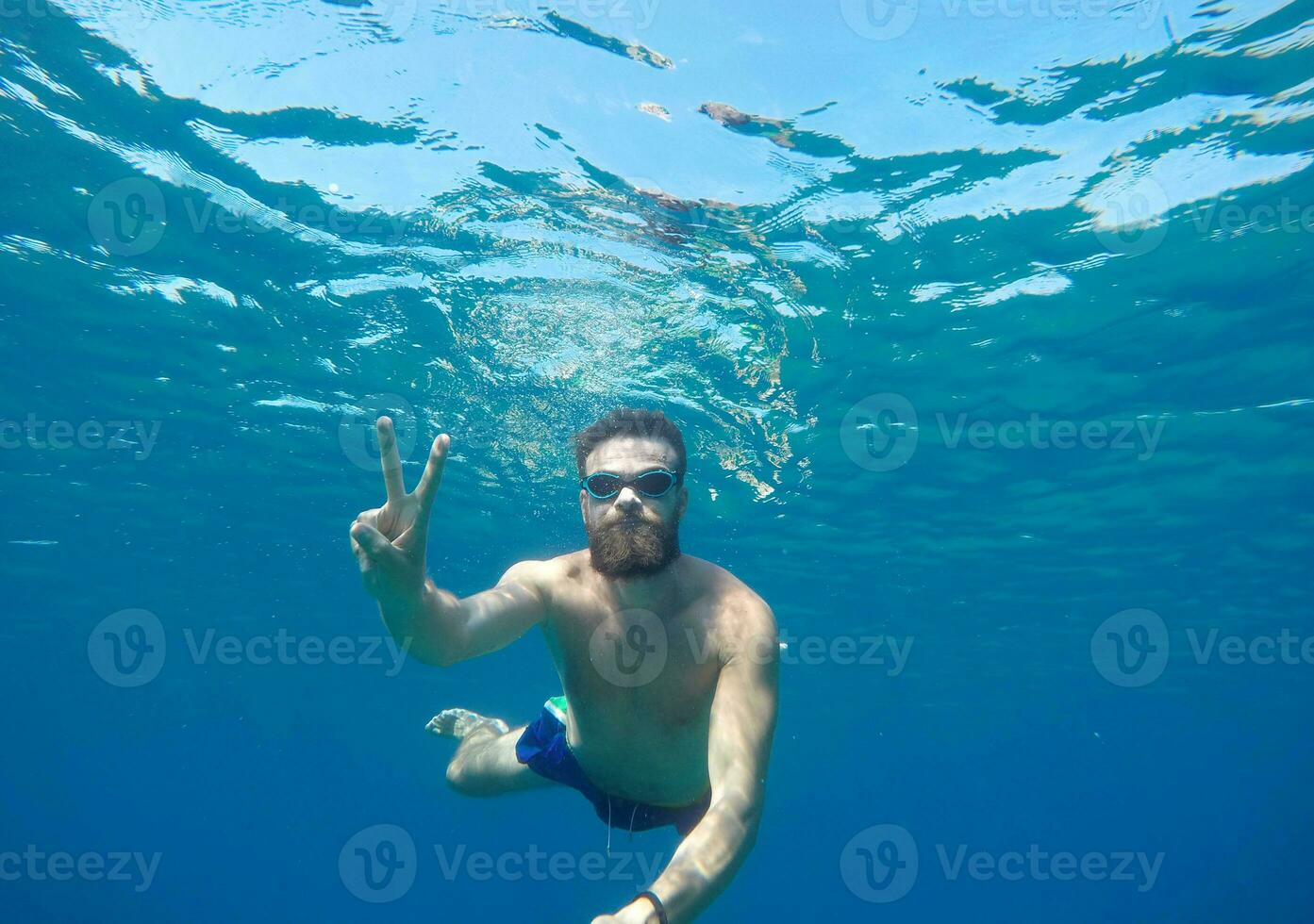 Beard man with mask diving in a blue clean water photo