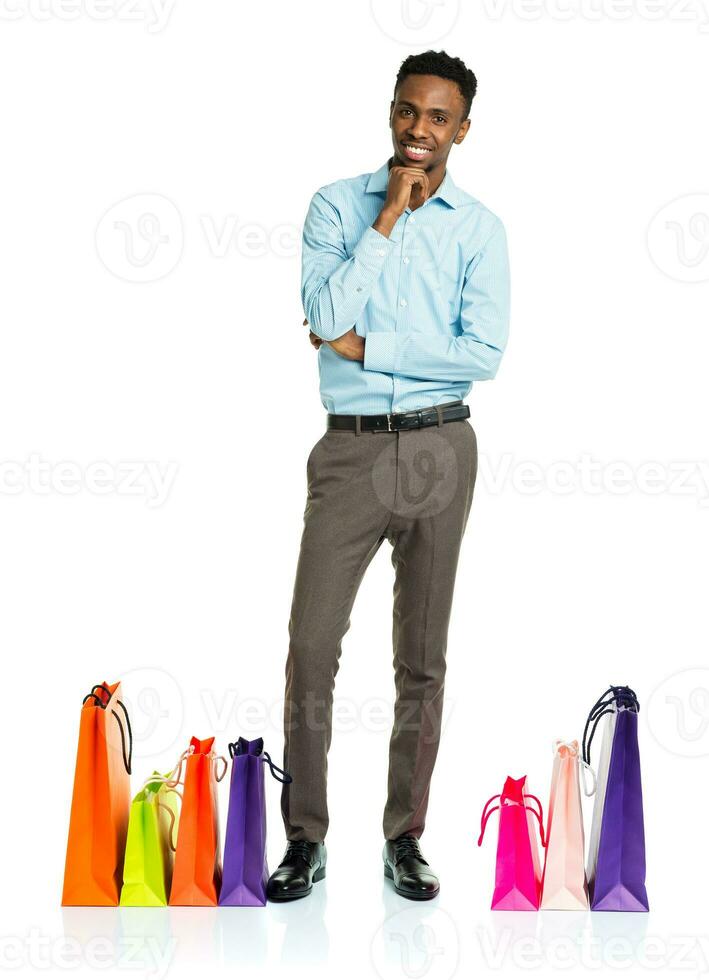 Happy african american man with shopping bags on white background photo