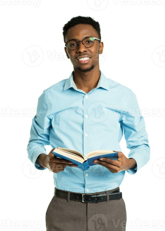 Happy african american college student with book in his hands standing on white photo