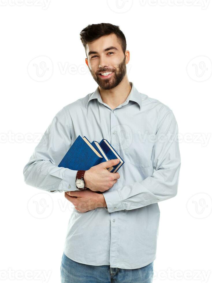 Young bearded smiling man with books in hands on white photo