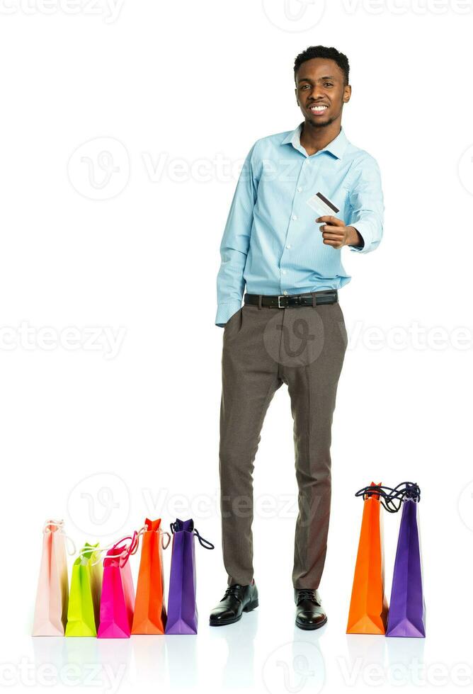 contento africano americano hombre con compras pantalones y participación crédito tarjeta en blanco antecedentes foto