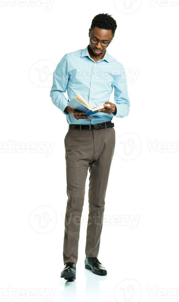 Happy african american college student with books in his hands  standing on white photo