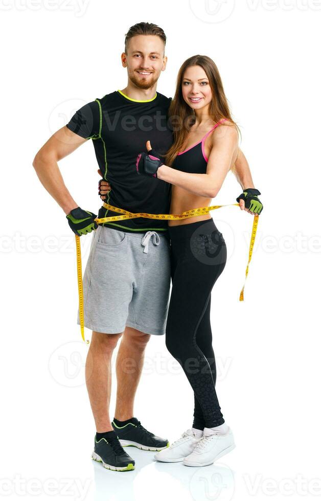 Happy athletic couple - man and woman with measuring tape on and ginger up the white photo