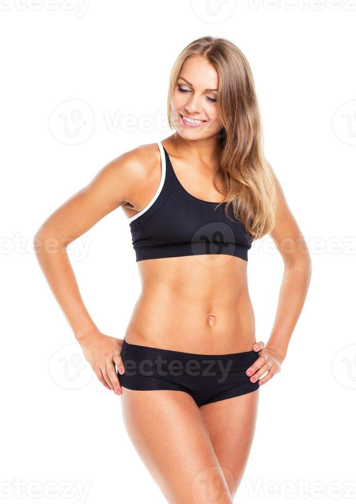 Young sports girl does exercises on a white photo