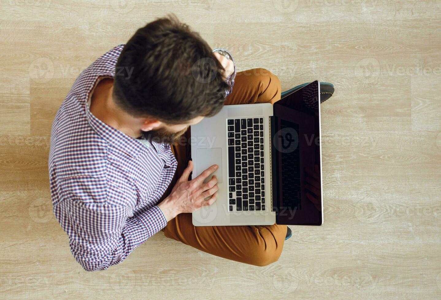 Top view of man sitting on the floor and working with a laptop photo