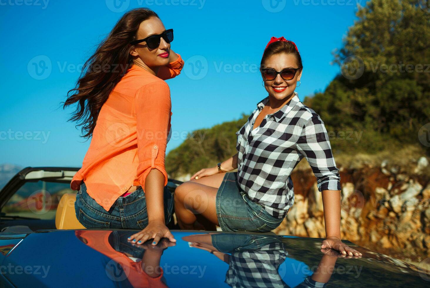 dos joven muchachas teniendo divertido en el cabriolé al aire libre foto