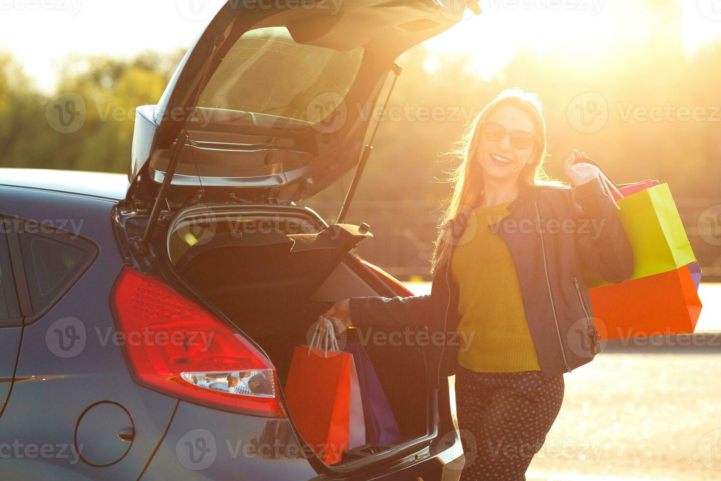 Caucasian woman putting her shopping bags into the car trunk photo